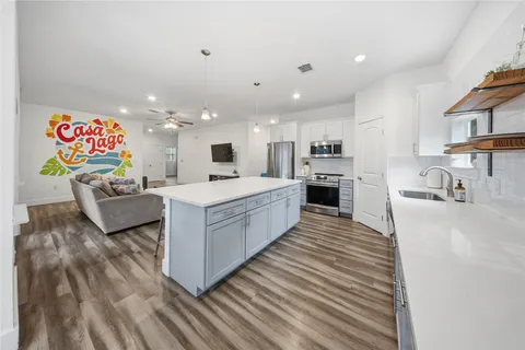 a large white kitchen with cabinets a sink and a stove