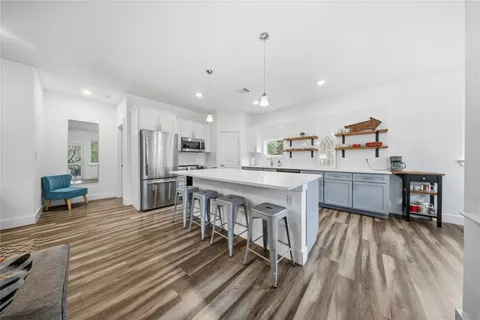 a kitchen with stainless steel appliances kitchen island granite countertop a sink cabinets and wooden floor
