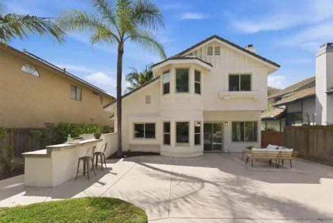 a view of a white house with a yard patio and furniture