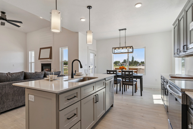 5777 West 4100 South Hooper, UT 84315 - Photo 41 of 41 Kitchen featuring gray cabinets, decorative light fixtures, light stone counters, an island with sink, and open floor plan