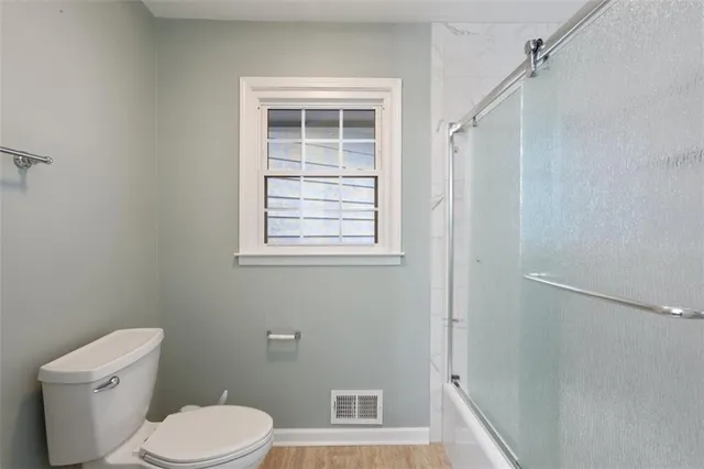 a view of an empty room with a window and kitchen view