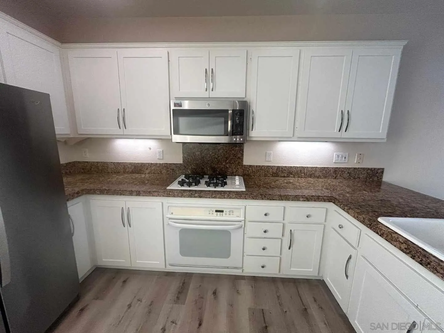 9408 Questa Pointe San Diego, CA 92126 - Photo 2 of 11 a kitchen with granite countertop white cabinets white stainless steel appliances and a sink
