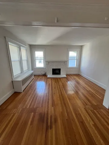 wooden floor fireplace and windows in an empty room