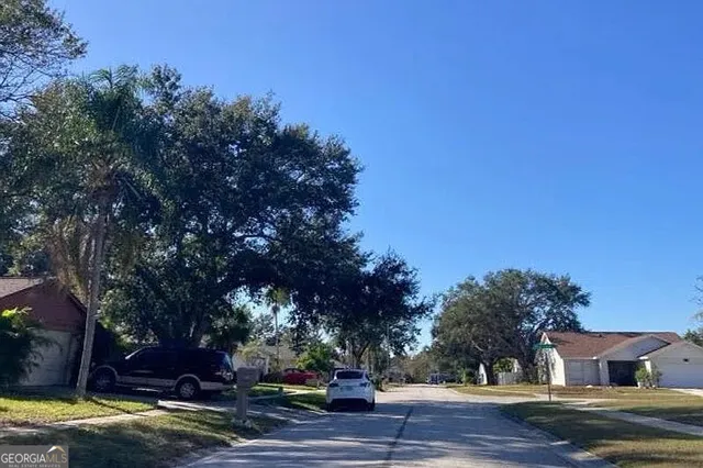 a view of a house with a yard and large trees