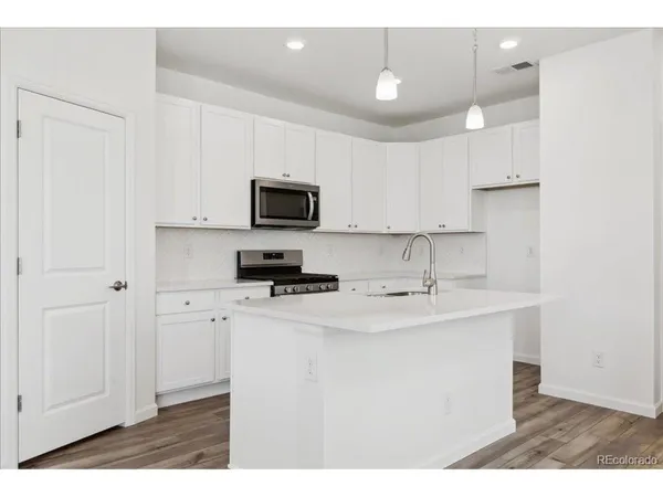 a kitchen with stainless steel appliances a sink a stove a refrigerator a center island and cabinets