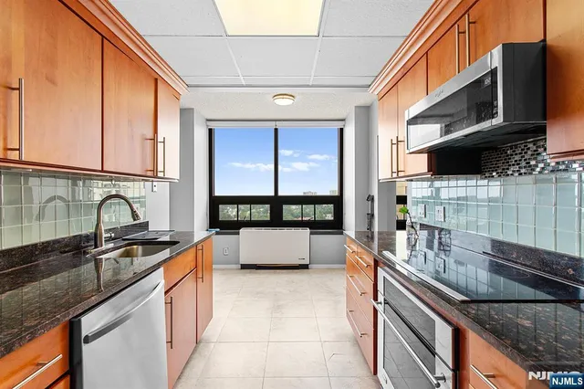 a kitchen with stainless steel appliances granite countertop a sink a stove and cabinets