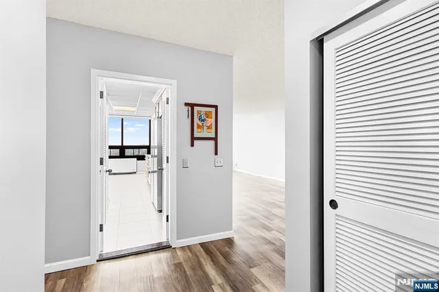 a view of a hallway with wooden floor and closet