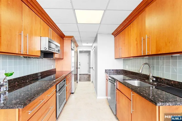 a kitchen with stainless steel appliances granite countertop a sink a stove and a wooden cabinets