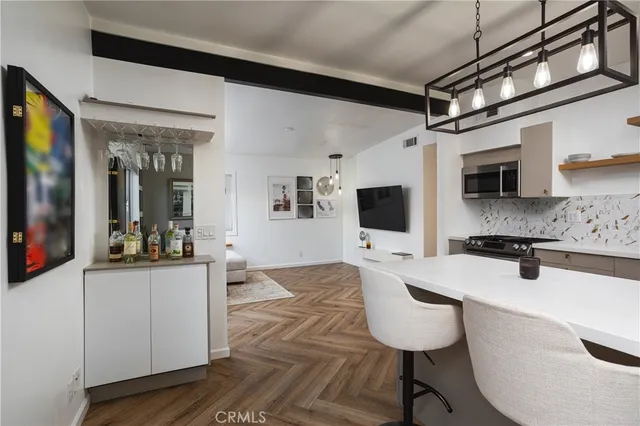 a living room with stainless steel appliances furniture a flat screen tv and a refrigerator