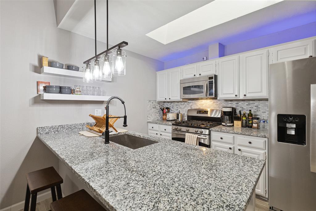 19016 Tupelo Lane Dallas, TX 75007 - Photo 8 of 28 a kitchen with granite countertop a stove a sink and a microwave