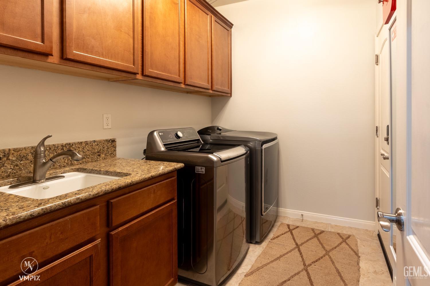 Undisclosed Address Bakersfield, CA 93311 - Photo 38 of 55 a utility room with granite countertop cabinets washer and dryer