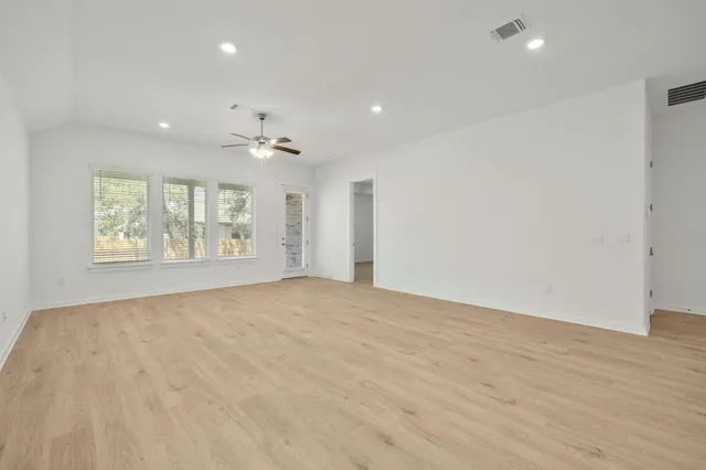 an empty room with windows and ceiling fan