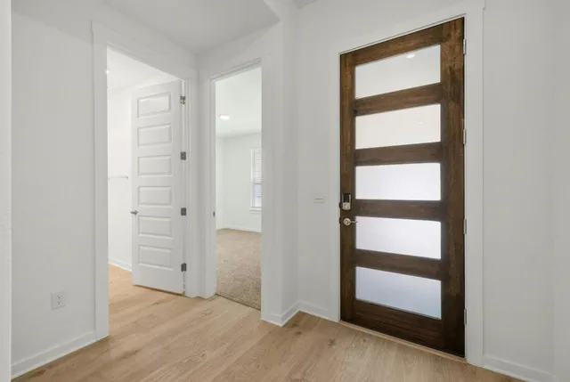 an empty room with wooden floor closet and windows