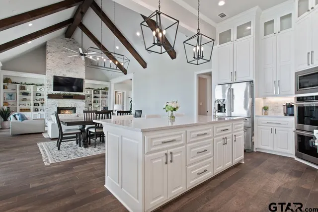 a kitchen with stainless steel appliances kitchen island granite countertop a table chairs in it and a wooden floor