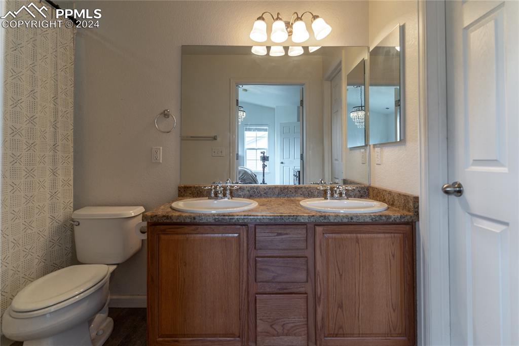1166 Walters Point Monument, CO 80132 - Photo 11 of 21 a bathroom with a granite countertop toilet a sink and a mirror