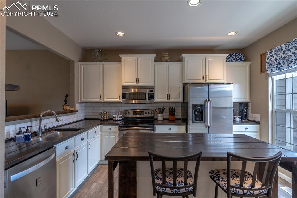 1166 Walters Point Monument, CO 80132 - Photo 5 of 21 a kitchen with stainless steel appliances a sink a stove a refrigerator cabinets and a dining table