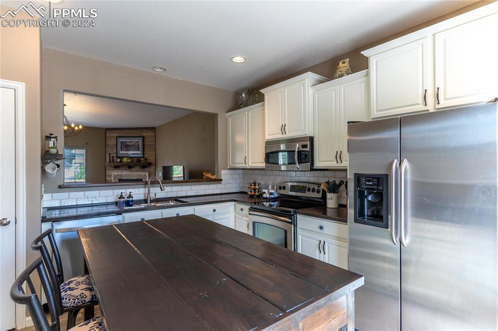 1166 Walters Point Monument, CO 80132 - Photo 6 of 21 a kitchen with stainless steel appliances granite countertop a stove a sink a refrigerator a microwave and cabinets