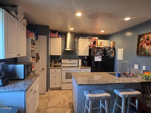 a kitchen with stainless steel appliances granite countertop a kitchen island a stove a table and chairs
