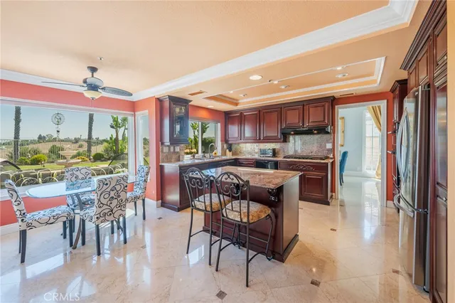 a kitchen with stainless steel appliances kitchen island granite countertop a table chairs and a refrigerator
