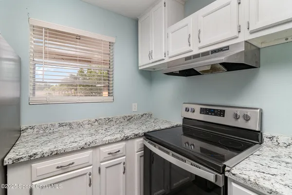 a kitchen with granite countertop a stove and a white cabinets