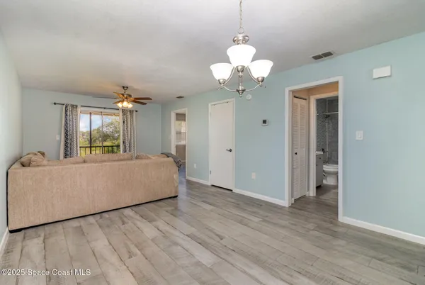 a living room with a bed furniture chandelier and a rug