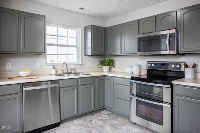 a kitchen with stainless steel appliances granite countertop a sink a stove a microwave a dining table and chairs