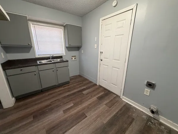 a kitchen with a sink and wooden floor