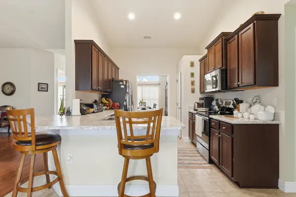 a kitchen with stainless steel appliances granite countertop a stove a sink dishwasher and a refrigerator with wooden cabinets