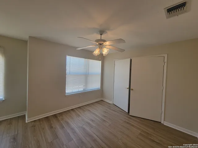 an empty room with wooden floor and windows