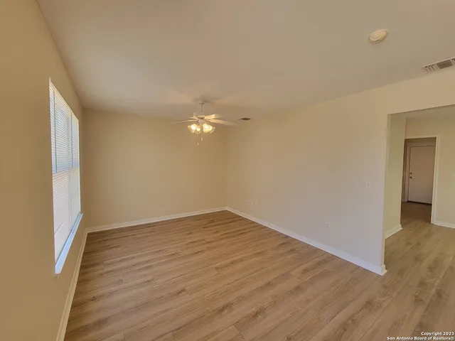 a view of an empty room with wooden floor and a window