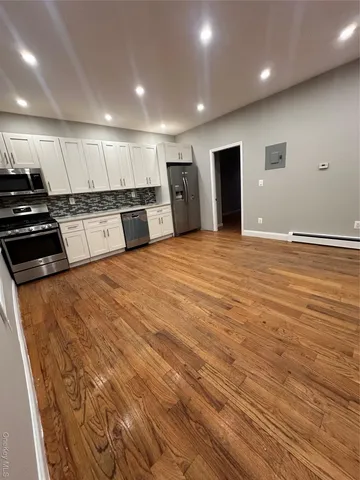 a large room with stainless steel appliances kitchen island granite countertop a stove and a refrigerator