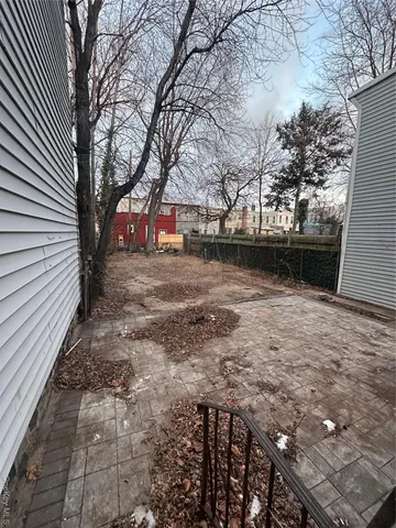 a view of backyard with wooden fence and large trees