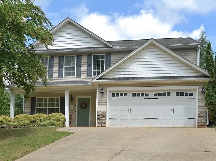 This two-story residence features a welcoming porch, an attached garage, and neatly manicured landscaping.