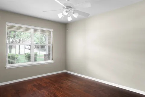 an empty room with a window and a fan