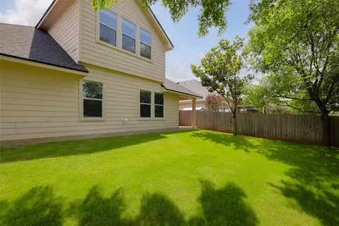 a backyard of a house with plants and wooden fence