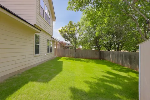 a view of a yard with large trees and a barn in it
