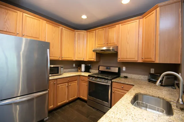 a kitchen with granite countertop a refrigerator stove top oven and sink