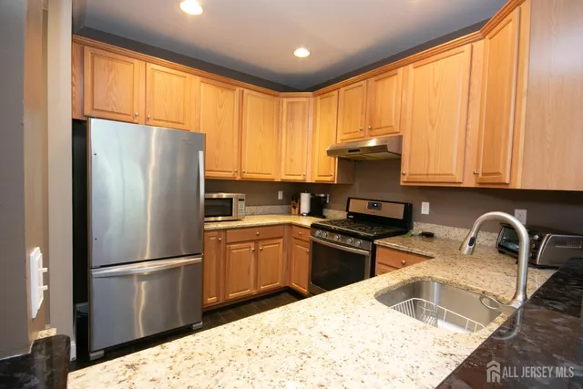a kitchen with granite countertop a refrigerator stove and sink