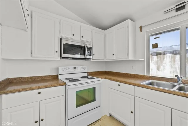 a kitchen with granite countertop white cabinets white stainless steel appliances and a sink