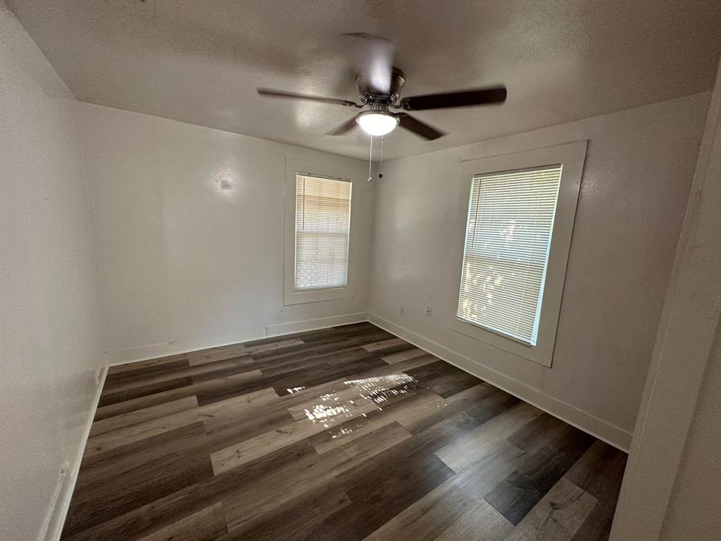 2206 Rockefeller Boulevard Dallas, TX 75203 - Photo 6 of 8 an empty room with wooden floor cabinet and windows