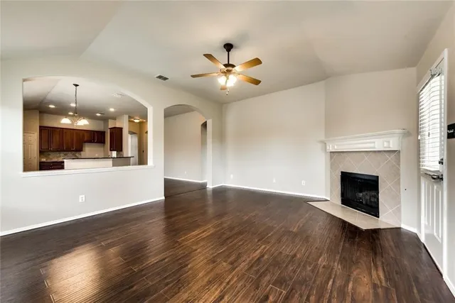 a view of an empty room with wooden floor and a kitchen