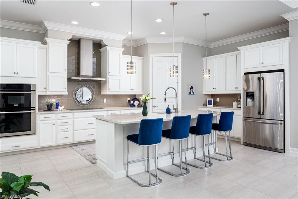 1423 Mockingbird Drive Naples, FL 34120 - Photo 9 of 32 a kitchen with stainless steel appliances kitchen island granite countertop a refrigerator a stove a sink a dining table and chairs with wooden floor