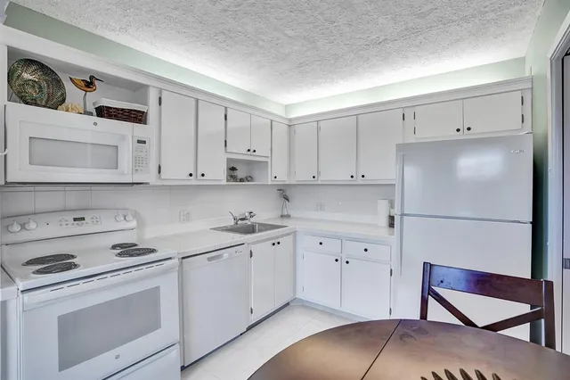 a kitchen with white cabinets and white appliances