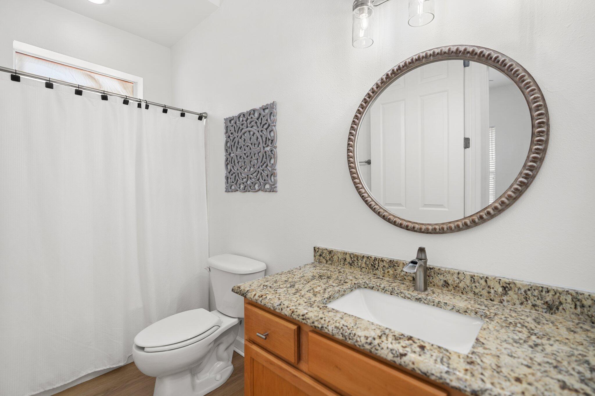 2221 Crystal Cove Lane, Unit 2221 Miramar Beach, FL 32550 - Photo 27 of 32 a bathroom with a granite countertop toilet a sink and a mirror