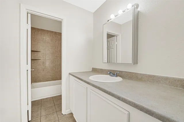 a bathroom with a granite countertop sink mirror and a bathtub