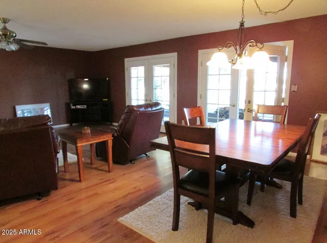 a dining room with wooden floor a chandelier a wooden table and chairs