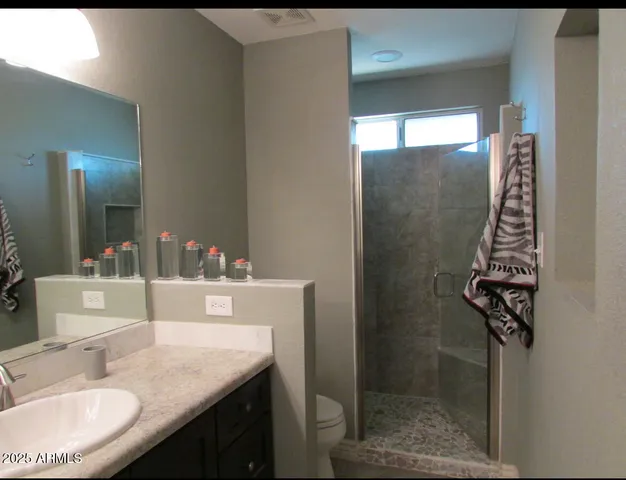 a bathroom with a granite countertop sink a mirror and shower