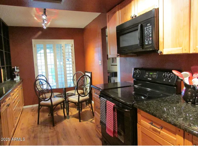 a kitchen with granite countertop wooden cabinets dining table and chairs