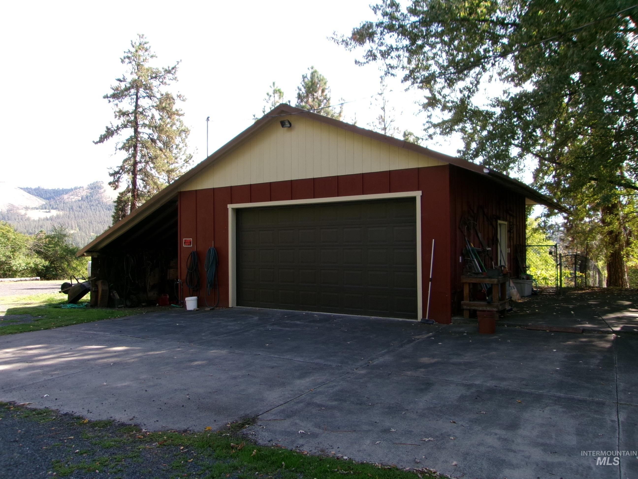 307 Locust Road Kamiah, ID 83536 - Photo 9 of 50 Detached garage with a dark-colored roll-up door, red siding, and light-colored gable