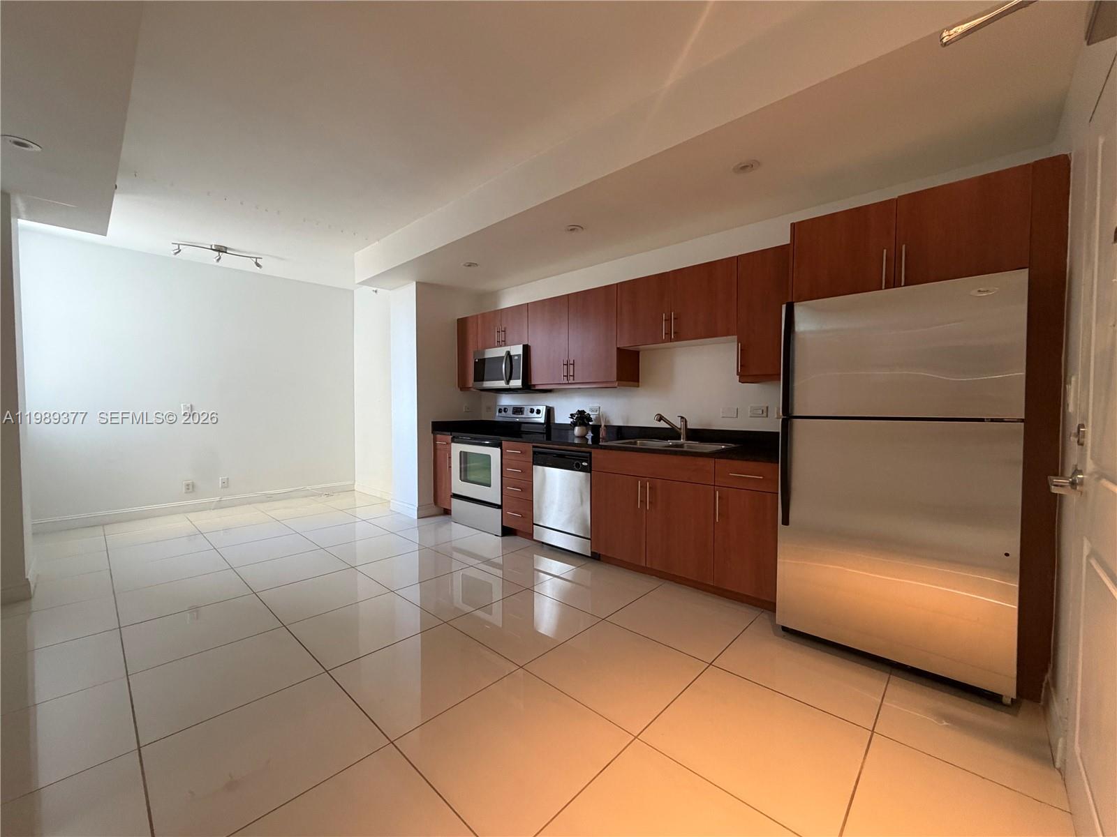 111 East Flagler Street, Unit 606 Miami, FL 33131 - Photo 1 of 10 a kitchen with granite countertop a refrigerator and a stove top oven
